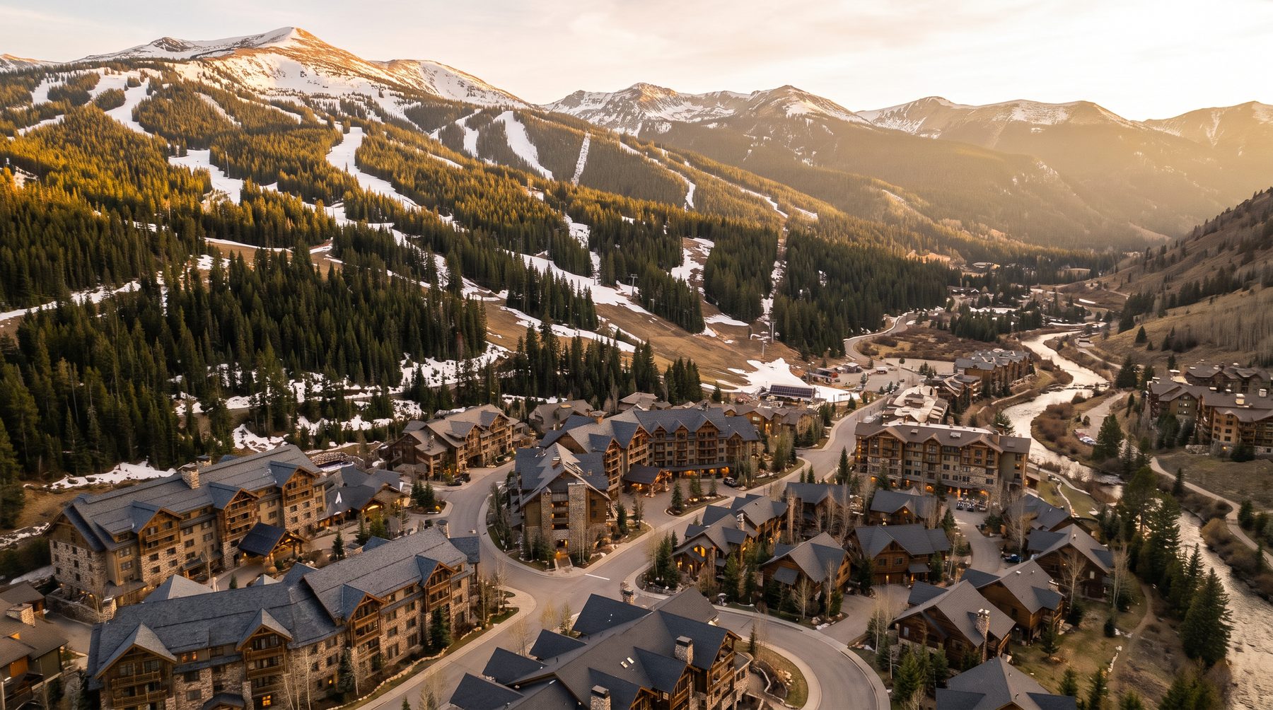 Wide aerial view of a western mountain resort valley with a lake and forested slopes